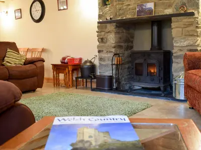 a living room with a stone fireplace and a table at Penrhiw in Llangeitho