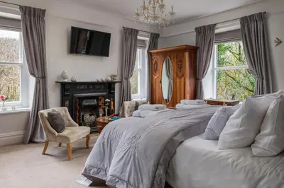 a bedroom with three beds and a fireplace and a tv at Afon Rhaiadr Country House in Dolgellau