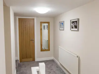 a hallway with a wooden door and a mirror at Hafan in Llangollen
