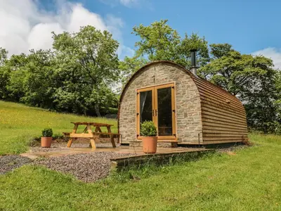 a small cabin with a picnic table in a field at Dingle Den in Hereford