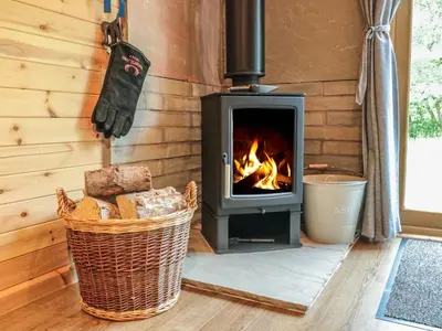 a fireplace in a log cabin with a fire at Dingle Den in Hereford