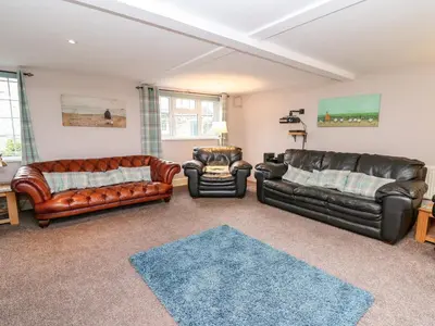 a living room with leather furniture and a blue rug at Fisher Granary in Lampeter