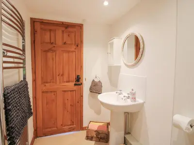 a bathroom with a sink and a wooden door at Old Hall Barn 4 in Church Stretton