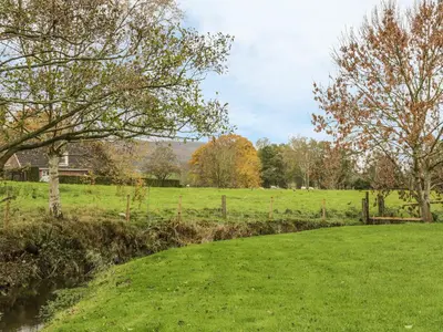 a grassy field with a fence and trees in the background at Old Hall Barn 4 in Church Stretton