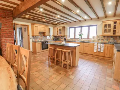 a large kitchen with wooden cabinets and a island with bar stools at Ty Berllan in Caersws