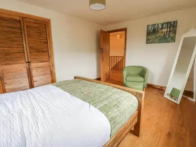 a bedroom with a bed and a green chair at Ty Berllan in Caersws