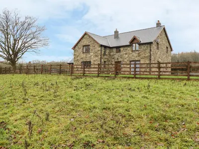 an old stone house in a field with a fence at Ty Berllan in Caersws