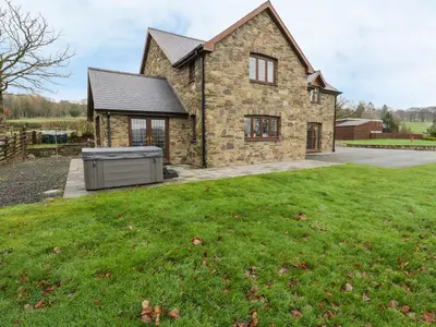 a stone house with a grill in a yard at Ty Berllan in Caersws