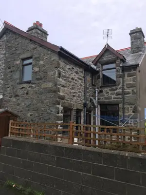 a stone house with a wooden fence in front of it at Heulwen in Barmouth