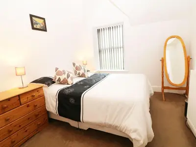 a bedroom with a bed and a dresser and a mirror at Heulwen in Barmouth