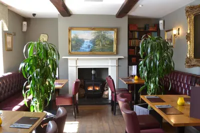 a restaurant with a fireplace and tables and chairs at The Nags Head in Montgomery