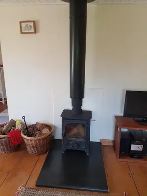a black stove in a room with a table at Seren Loft - Cynghordy, Llandovery in Llandovery