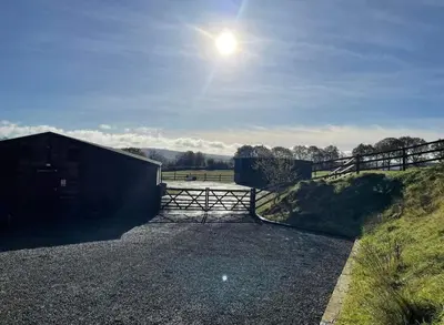 a gate in a field with the sun in the sky at Maes y Gwaelod in Llanwrtyd Wells
