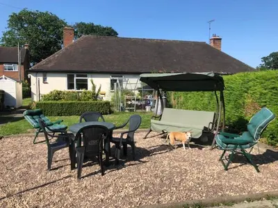 a patio with a table and chairs and a dog under a canopy at 11 Callow Crescent in Minsterley