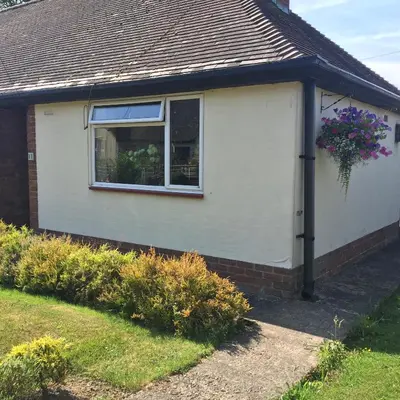 a white house with a window and a flower basket at 11 Callow Crescent in Minsterley