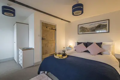 a bedroom with a bed with a blue blanket at Finest Retreats - Tegannedd - Luxury Grade II Listed Cottage With Hot Tub in Ffestiniog