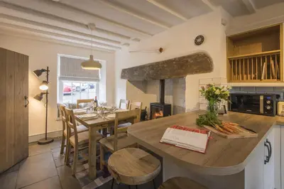 a kitchen and dining room with a table and a fireplace at Finest Retreats - Tegannedd - Luxury Grade II Listed Cottage With Hot Tub in Ffestiniog
