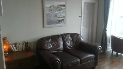 a brown leather couch in a living room with a table at Apartment Chic in Barmouth