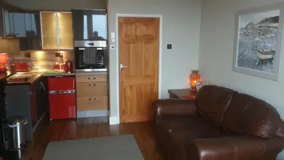 a living room with a couch and a kitchen at Apartment Chic in Barmouth