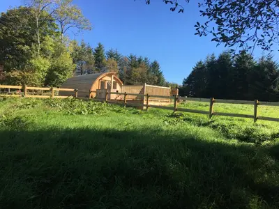 a barn in a field next to a fence at Brynllwyd Glamping in Devils Bridge