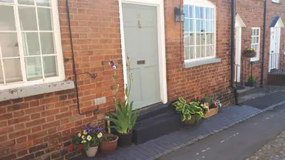 a brick building with potted plants and a white door at 19 Upper Linney in Ludlow