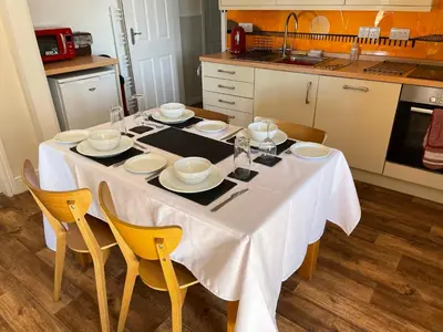 a kitchen with a table with white plates and chairs at Hawen - Barmouth in Barmouth