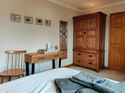 a bedroom with a bed and a wooden cabinet and a desk at Nant Gloyw Oswestry in Oswestry