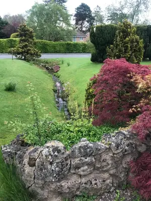 a garden with a stone wall and flowers at Nant Gloyw Oswestry in Oswestry