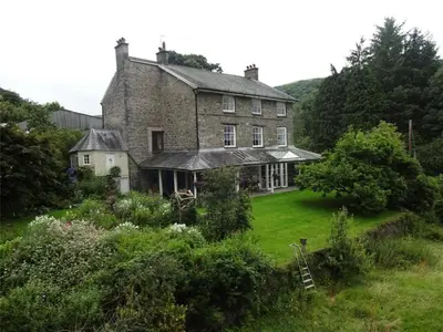an old brick house with a garden in front of it at Plas Esgair in Llanbrynmair