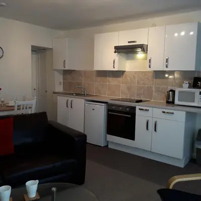 a kitchen with white cabinets and a black couch at Lucea Cottage in Craven Arms