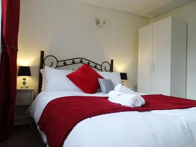a bedroom with a large bed with red and white pillows at Lucea Cottage in Craven Arms