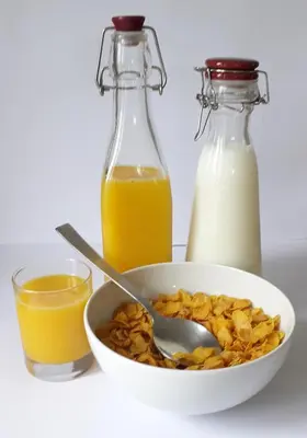 a bowl of cereal with a spoon and bottles of milk at Lucea Cottage in Craven Arms