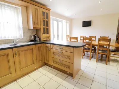 a kitchen with wooden cabinets and a table with chairs at Tyn Y Buarth in Dyffryn