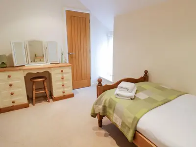 a bedroom with a bed and a dresser with a mirror at Tyn Y Buarth in Dyffryn