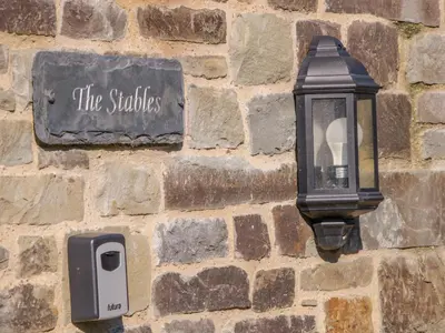 a light on a brick wall with a street sign at The Stables in Knighton