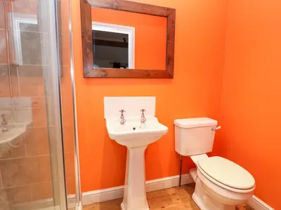 a bathroom with a toilet and a sink and a mirror at The Stables in Knighton