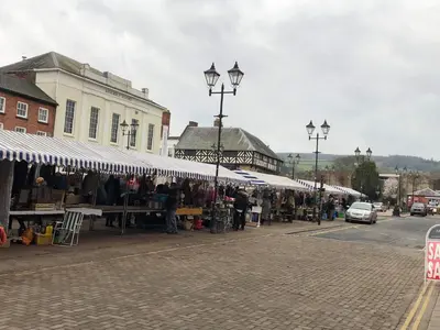 a group of people standing around a market with umbrellas at Flat G, 8 Castle Street in Ludlow