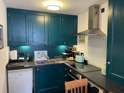 a kitchen with dark green cabinets and a sink at Flat G, 8 Castle Street in Ludlow
