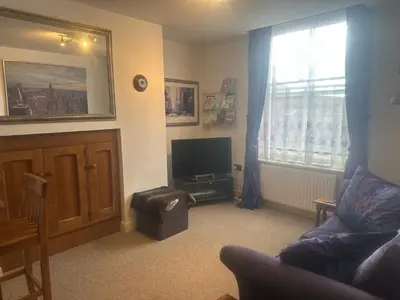a living room with a couch and a television at Flat G, 8 Castle Street in Ludlow