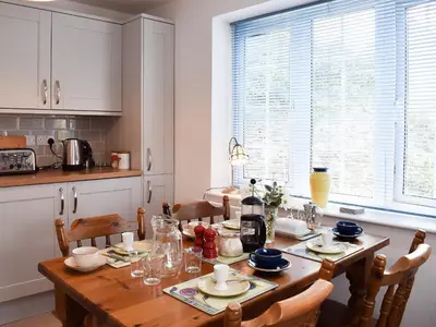 a kitchen with a wooden table with chairs and a dining room at Glasfor in Llanon