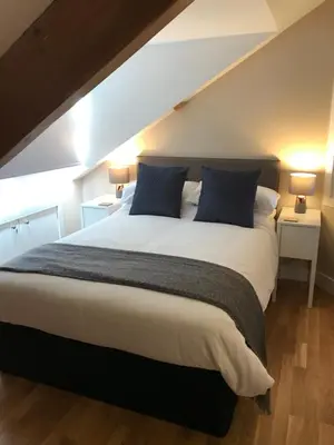 a bedroom with a large bed with blue pillows at Apartment 4, 1 Laura Place in Aberystwyth