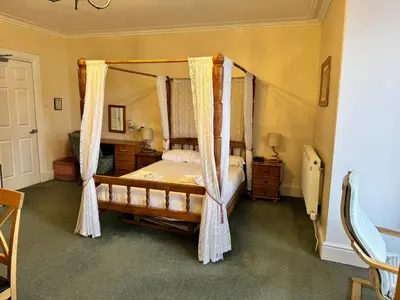 a bedroom with a canopy bed with curtains at Môr Wyn Guest House in Barmouth
