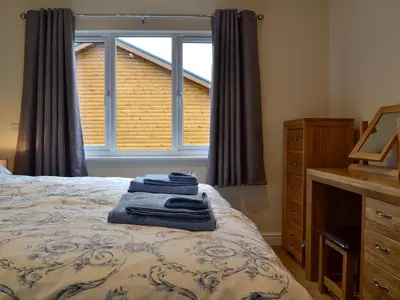 a bedroom with a bed with two blue towels on it at Bluebell Lodge in Llandrindod Wells