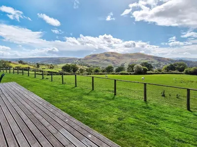 a wooden deck with a view of a green field at Bluebell Lodge in Llandrindod Wells