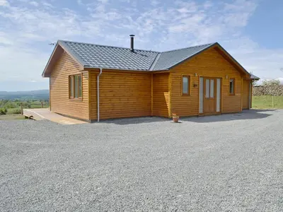 a small wooden house with a parking lot at Bluebell Lodge in Llandrindod Wells