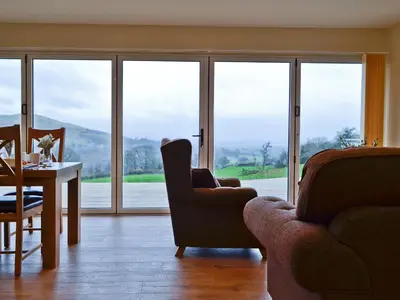 a living room with a table and chairs and windows at Bluebell Lodge in Llandrindod Wells