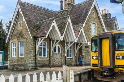 a train is parked in front of a building at Station Cottage in Bucknell