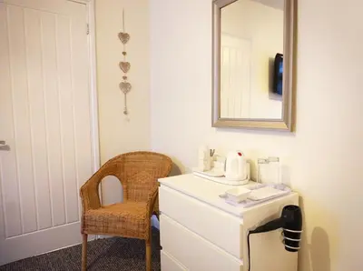 a bathroom with a mirror and a dresser and a chair at Borthwenbnb in Dolgellau