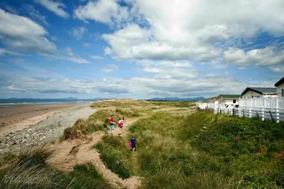 a family walking along a sandy beach at 92 Barmouth Bay Holiday Park in Llanddwywe