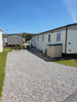 a gravel driveway in front of a row of mobile homes at 92 Barmouth Bay Holiday Park in Llanddwywe